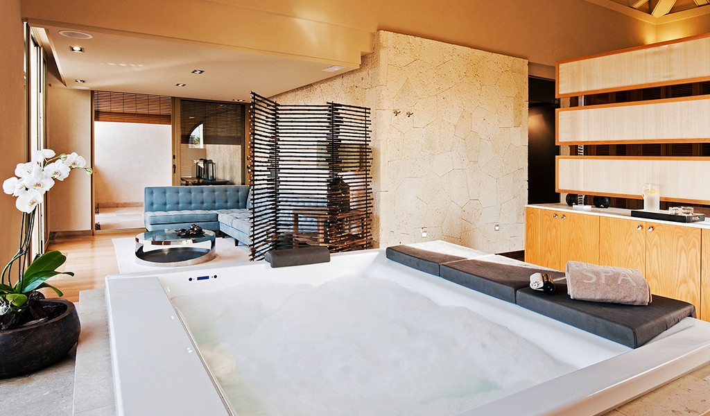Jacuzzi dans une salle de spa avec canapé bleu et orchidée blanche à Tenerife.