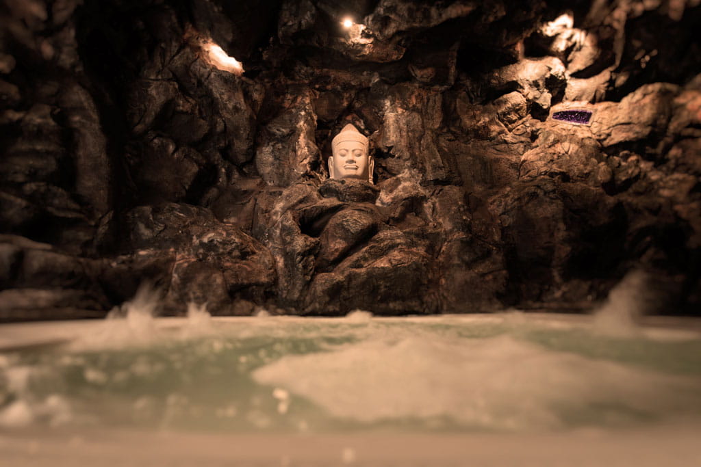 Buste de Bouddha dans une grotte rocheuse avec de l’eau à la base à Tenerife.