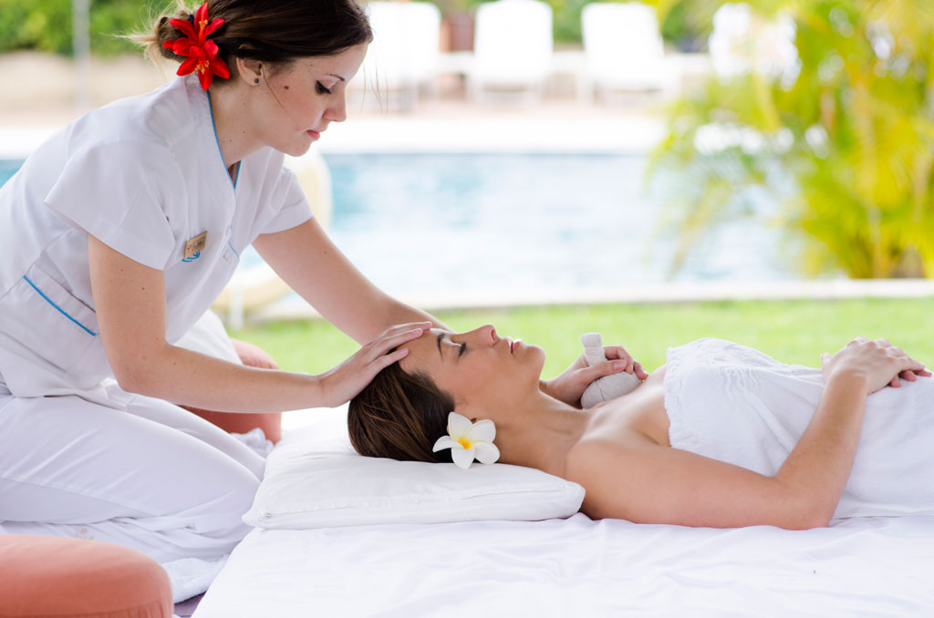 Un thérapeute donne un massage à une femme allongée près de la piscine à Tenerife.
